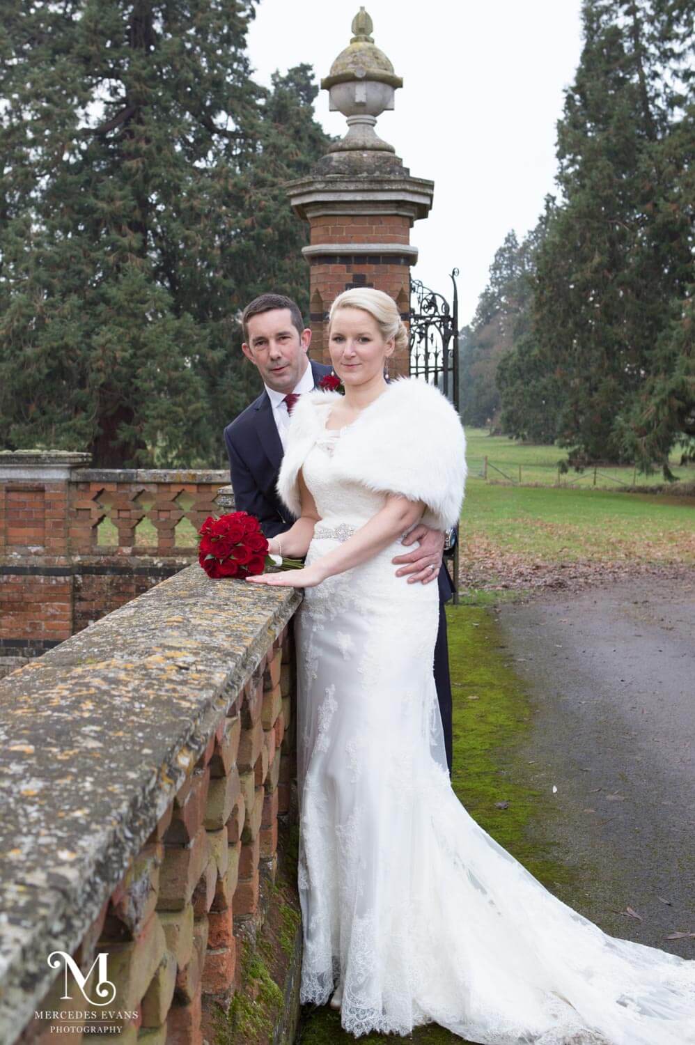 the newly weds lean together against the bridge railings