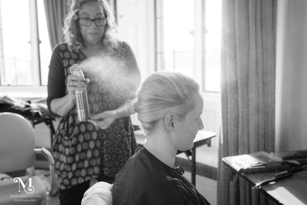 the hairderesser applies hairspray to the bride's hair at the elvetham hotel