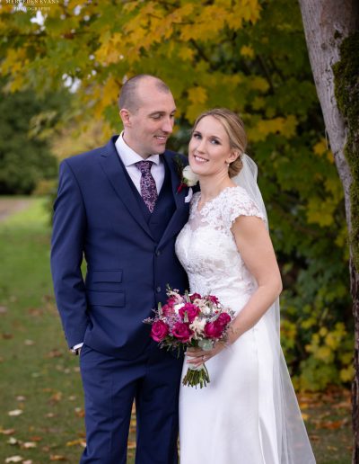 te newly weds pose in front of an autumnal tree