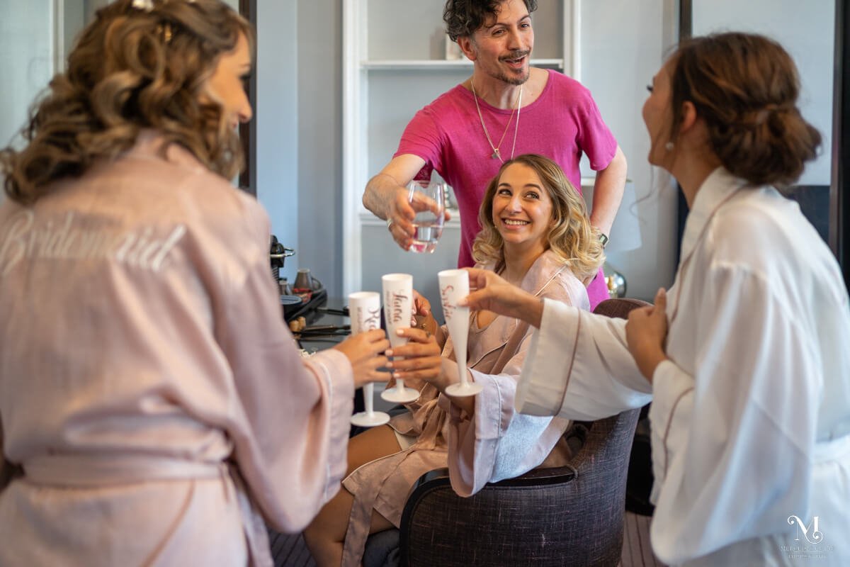 the bride, bridesmaids and her uncle celebrate with champagne before the wedding