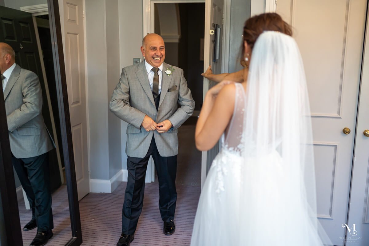 the father of the bride sees his daughter in her wedding dress and veil for the first time