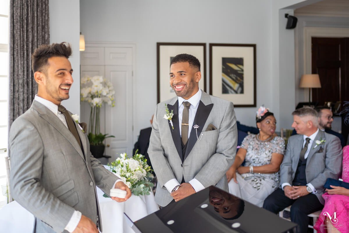 the groom shares a laugh with his best man as they wait for the bridal party to arrive