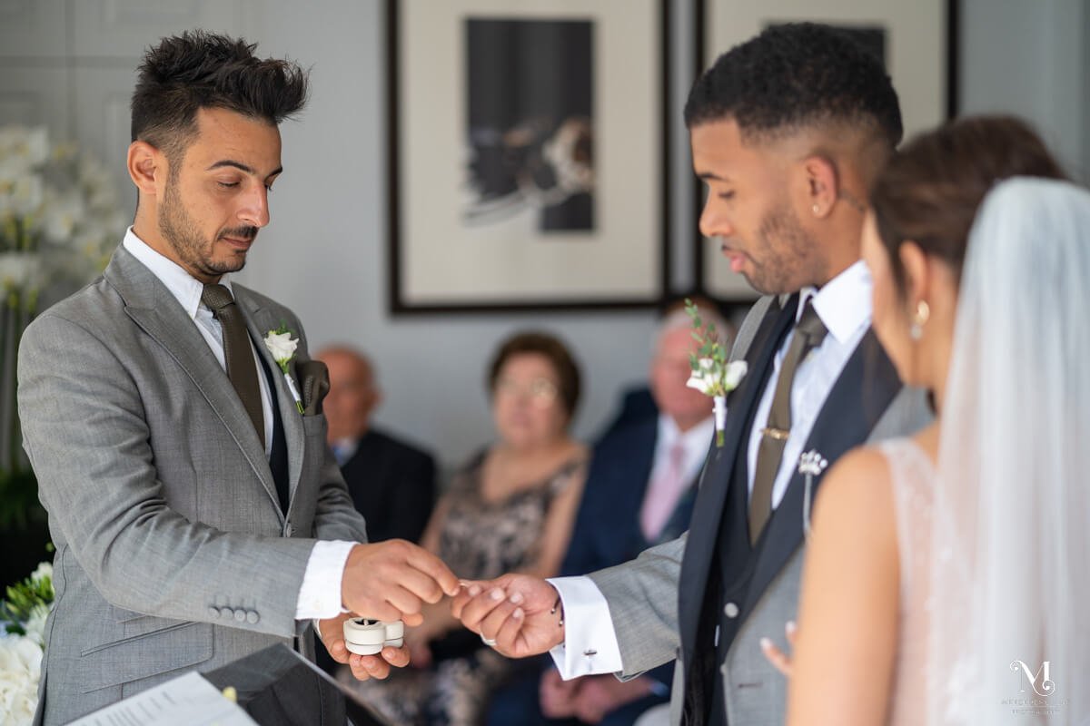 the best man hands the groom the wedding ring for the bride