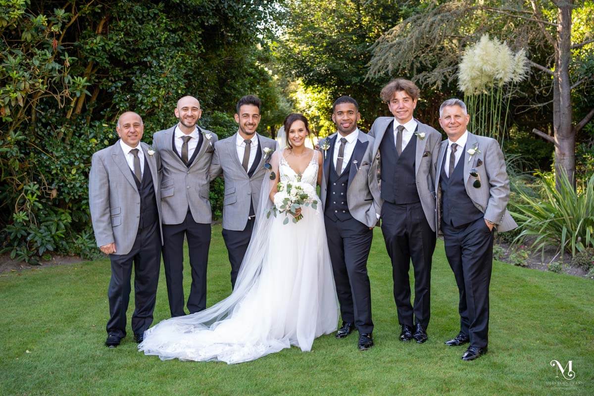 the bride and groom pose for a group photo with the groomsmen