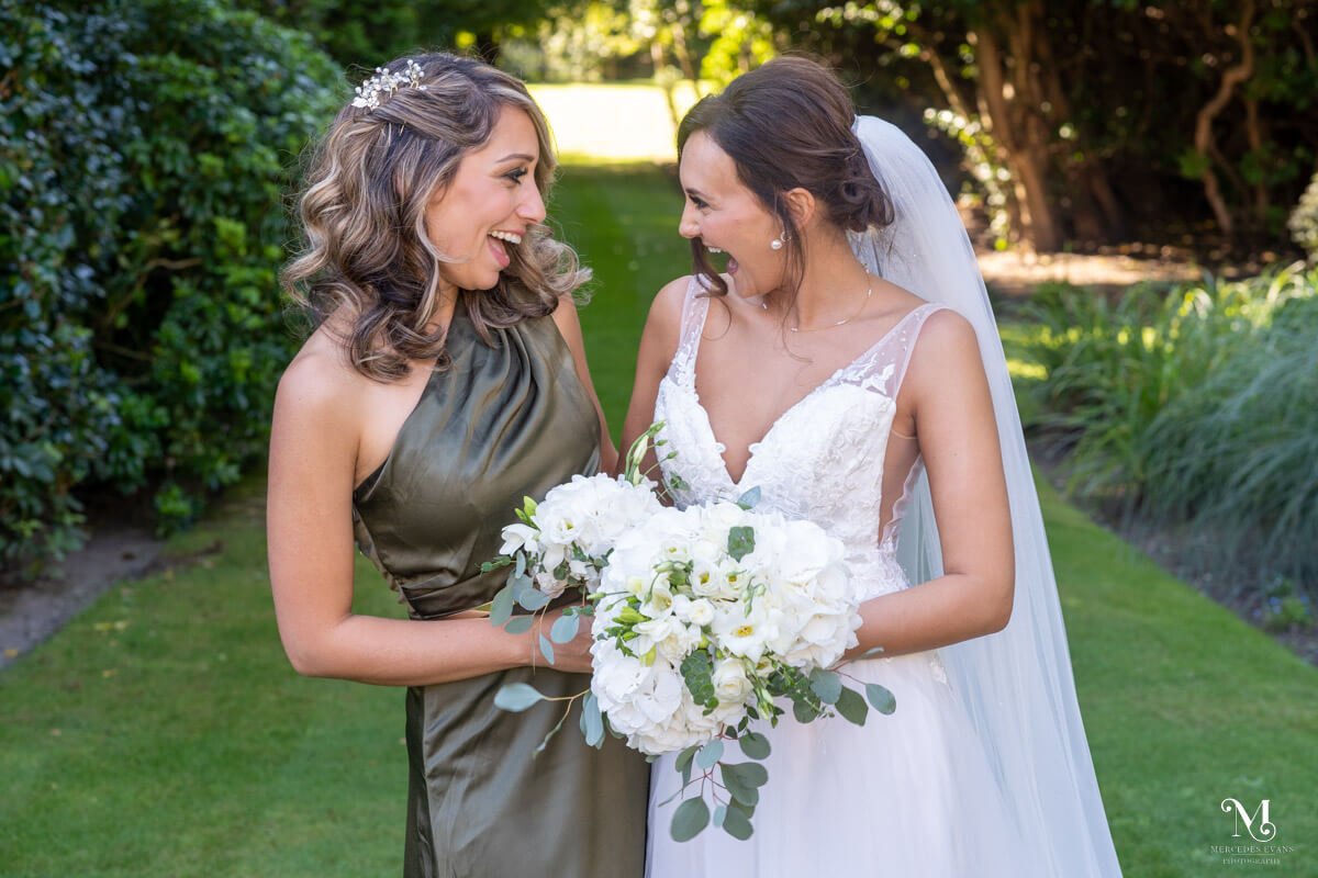the bride shares a laugh with her bridesmaid in the gardens at Gorse Hill