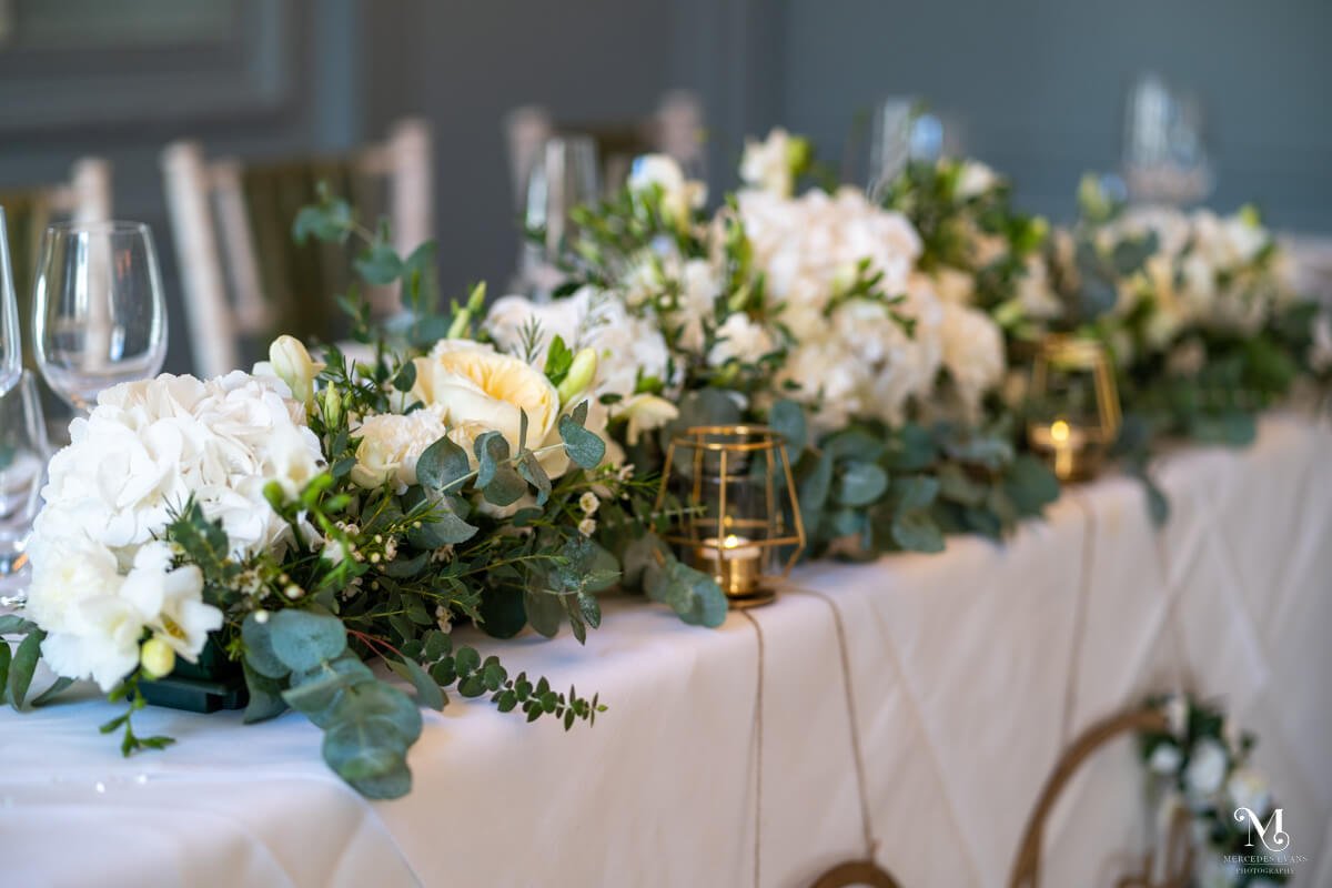 white hydrangeas and green eucalyptus foliage adorn the top table