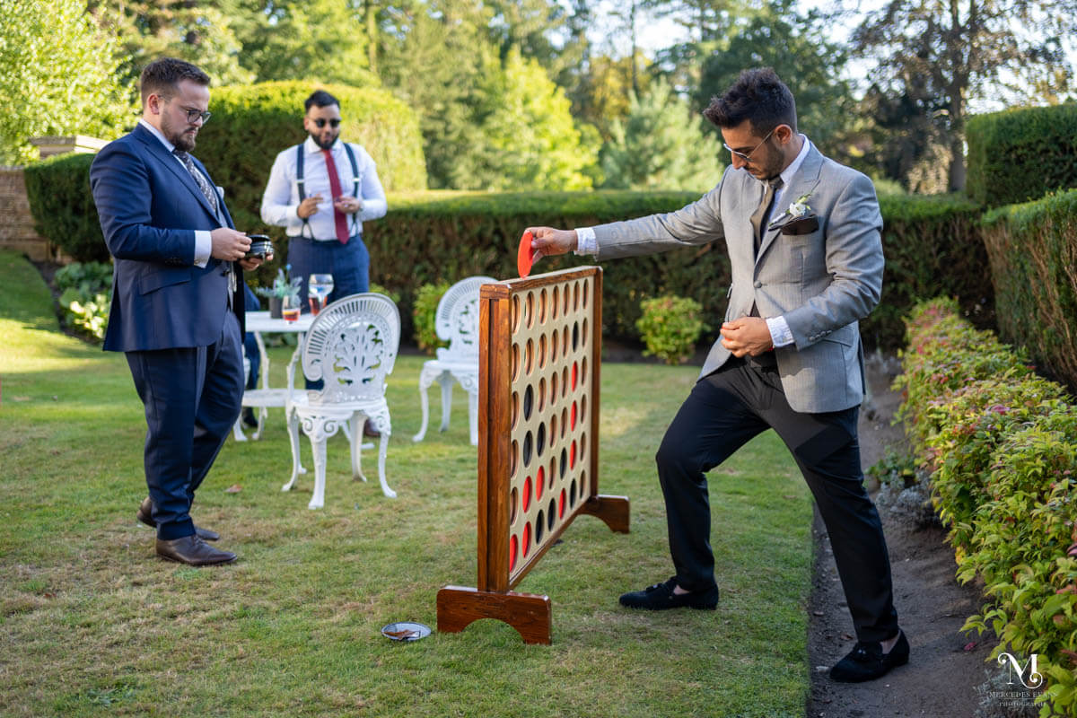 wedding guests play giant connect four in the garden during the wedding drinks reception