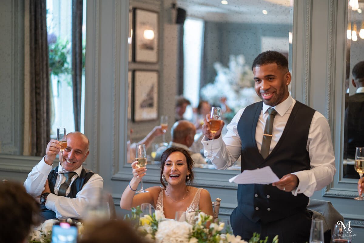 the groom and top table raise their glasses to the bridesmaids during his speech 