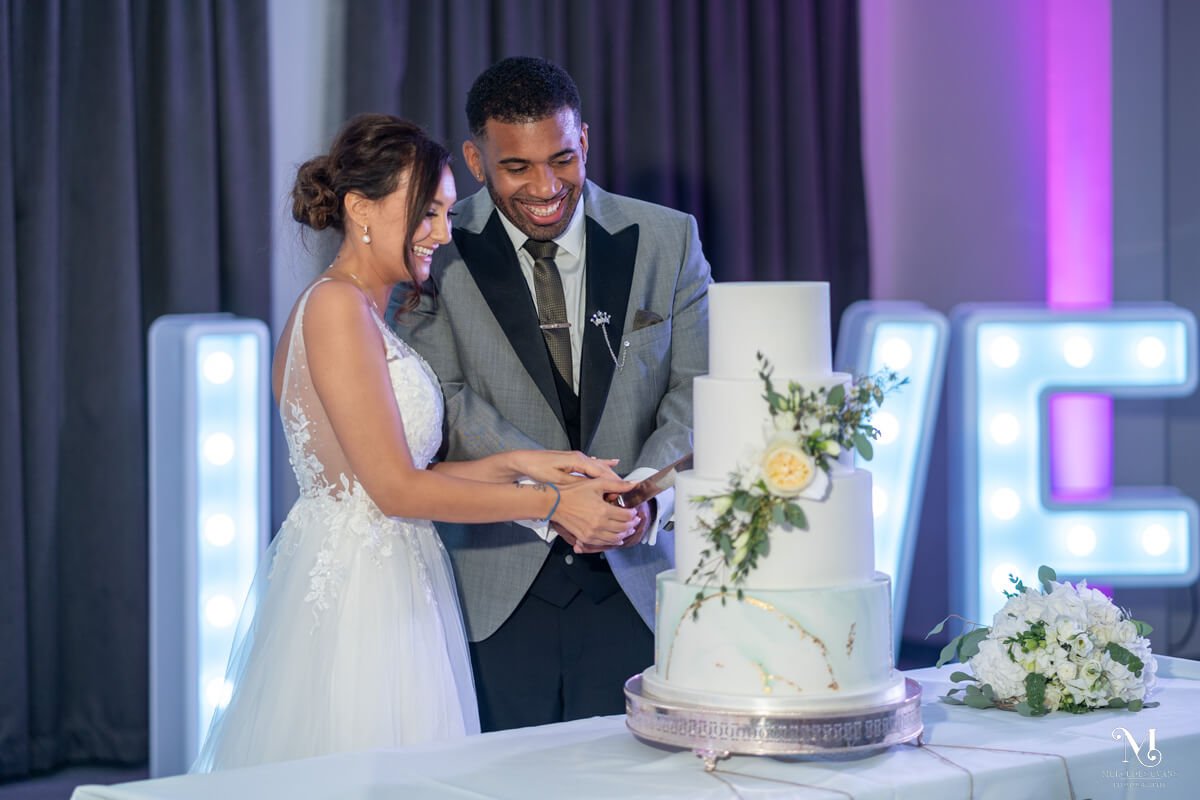 the bride and groom cut their four tiered wedding cake