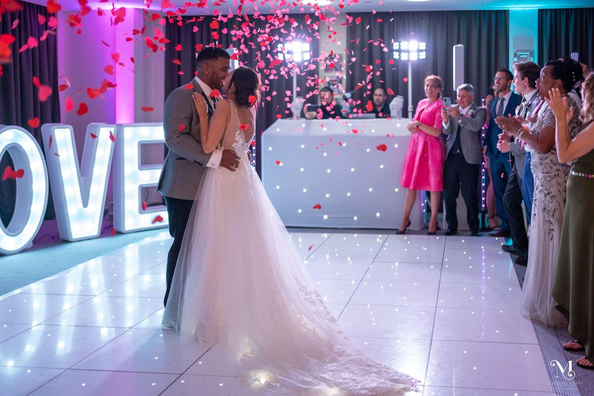 the bride and groom have their first dance as love heart confetti rains down on them