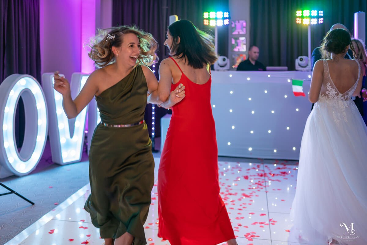 female wedding guests swing each other round on the dance floor