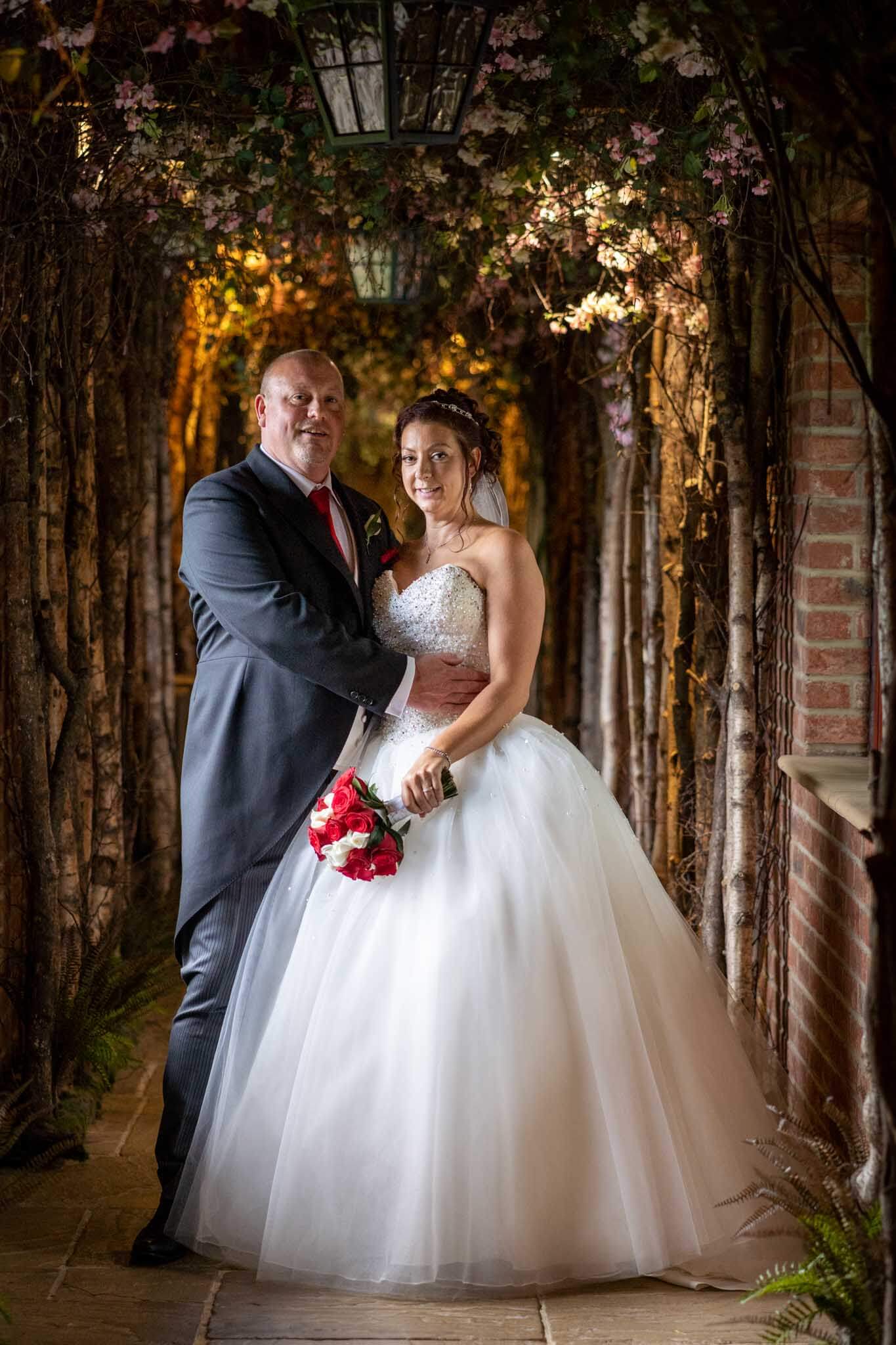 newly married couple stand together in the outdoor corridor at pennyhill park hotel