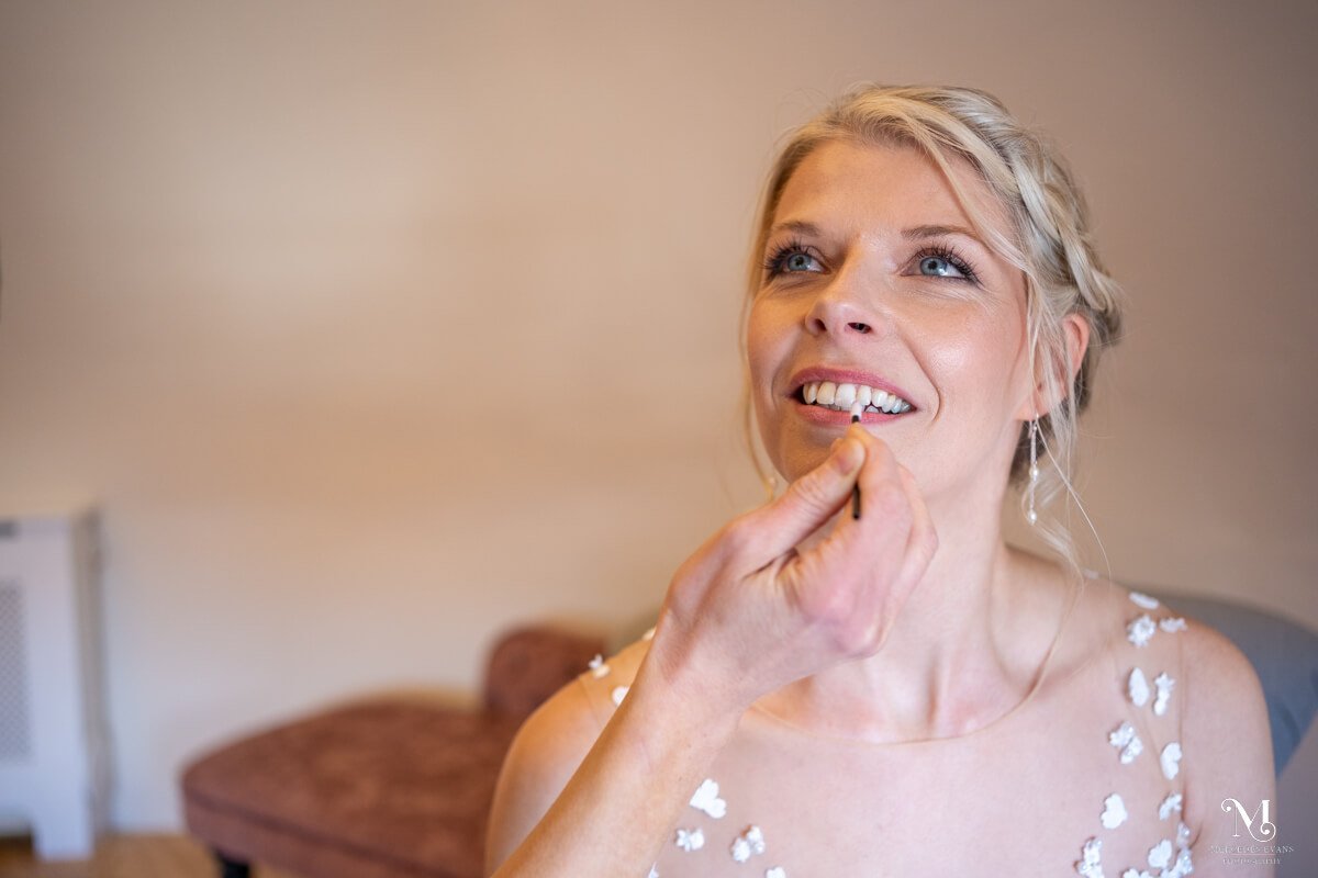 the bride has make up touch ups before the wedding