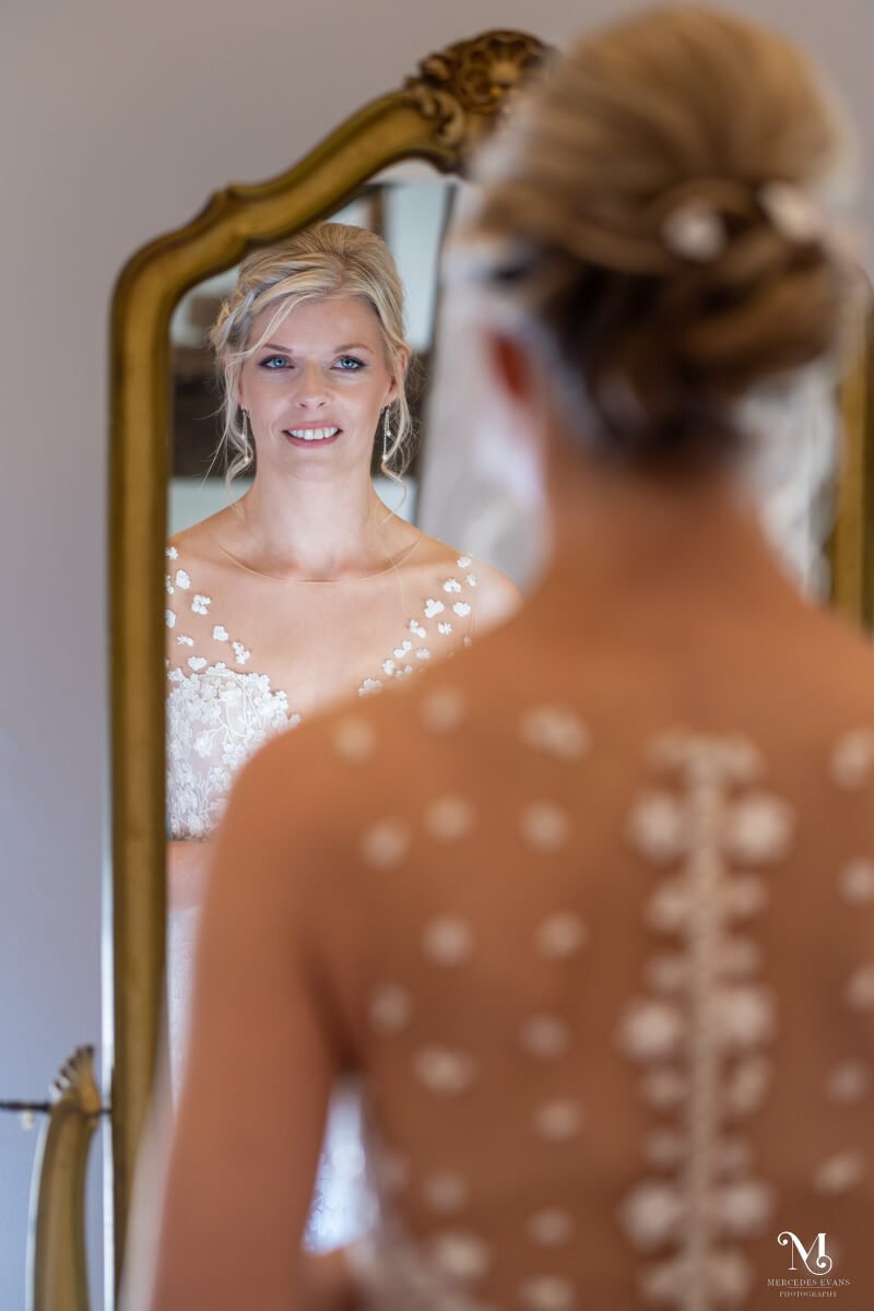 the bride looks at her reflection in the mirror