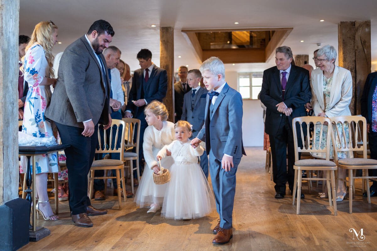 the small flower girl carrying a flower basket is led up the aisle by a page boy 