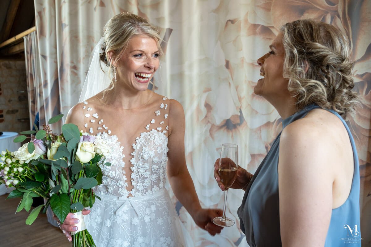 the bride laughs with one her bridesmaids during the drinks reception