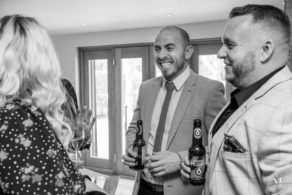 a group of guests enjoy a joke together during the wedding drinks reception