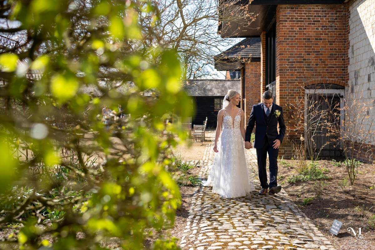 the bride and groom walk hand in hand down a cobbled path