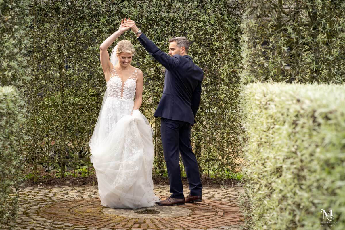 the groom stands and twirls his bride in the venue gardens