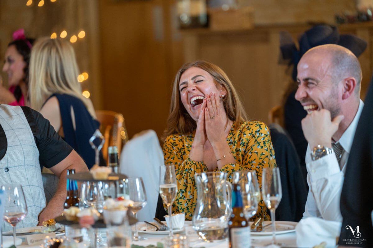 a female guest laughs and claps at a joke