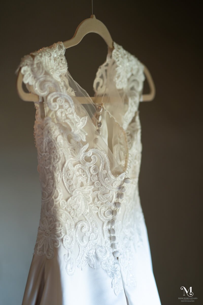 close up of the back of an ivory wedding dress with lace from the waist up, small back buttons and cap sleeves