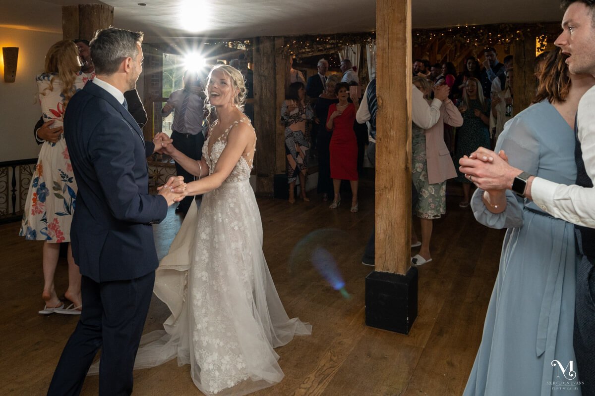 the bride sings as she holds the groom's hands and they dance together at their wedding surrounded by other dancers