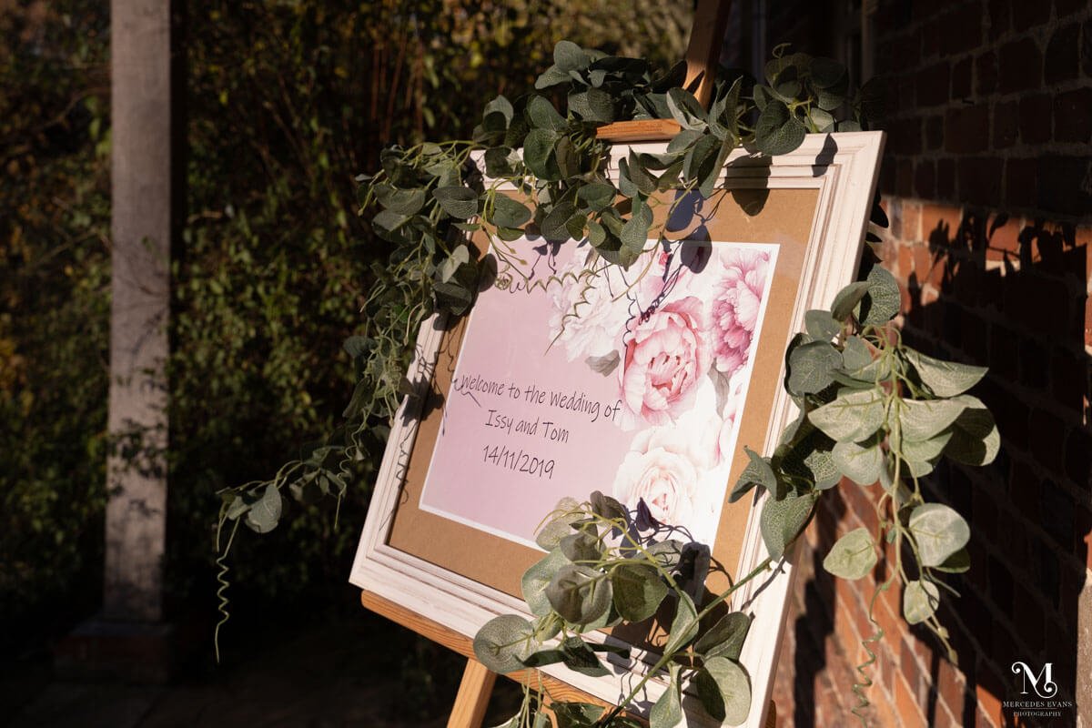 an easel announces the wedding, it is draped with eucalyptus greenery
