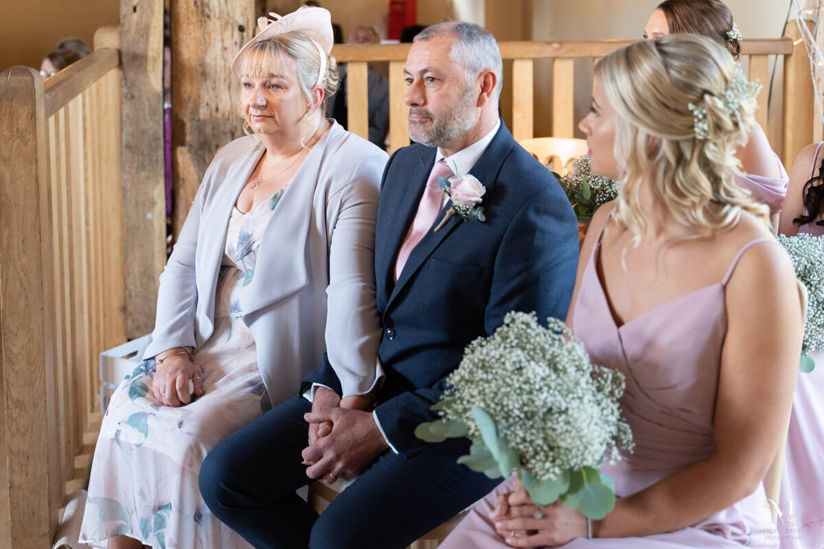 the mother and father of the bride hold hands as they sit and watch the couple get married