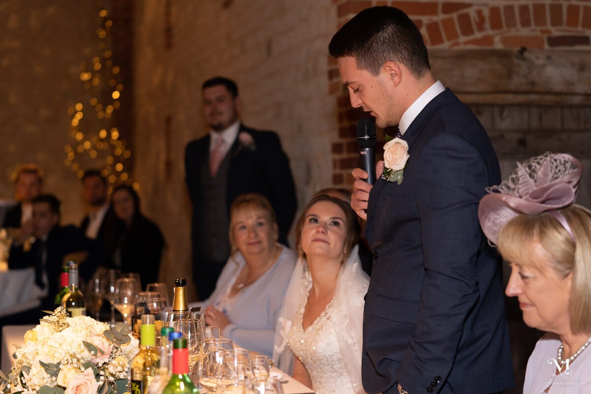 the tearful bride looks up at her new husband as he gives his speech