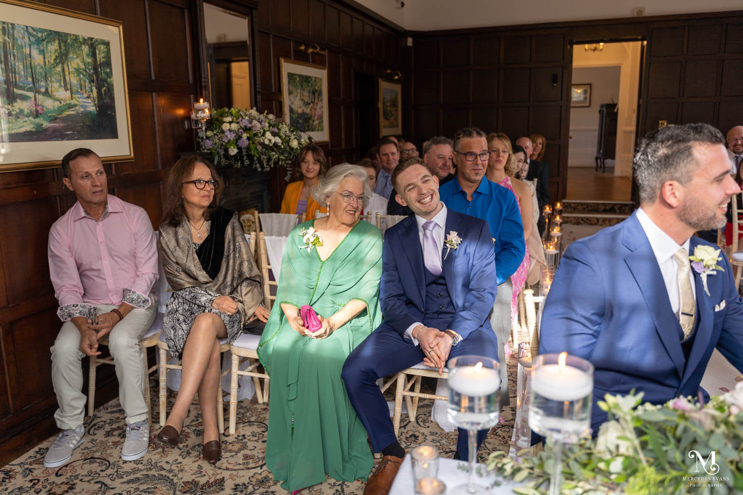 wedding guests laugh during the ceremony in the Oak room at Cantley House