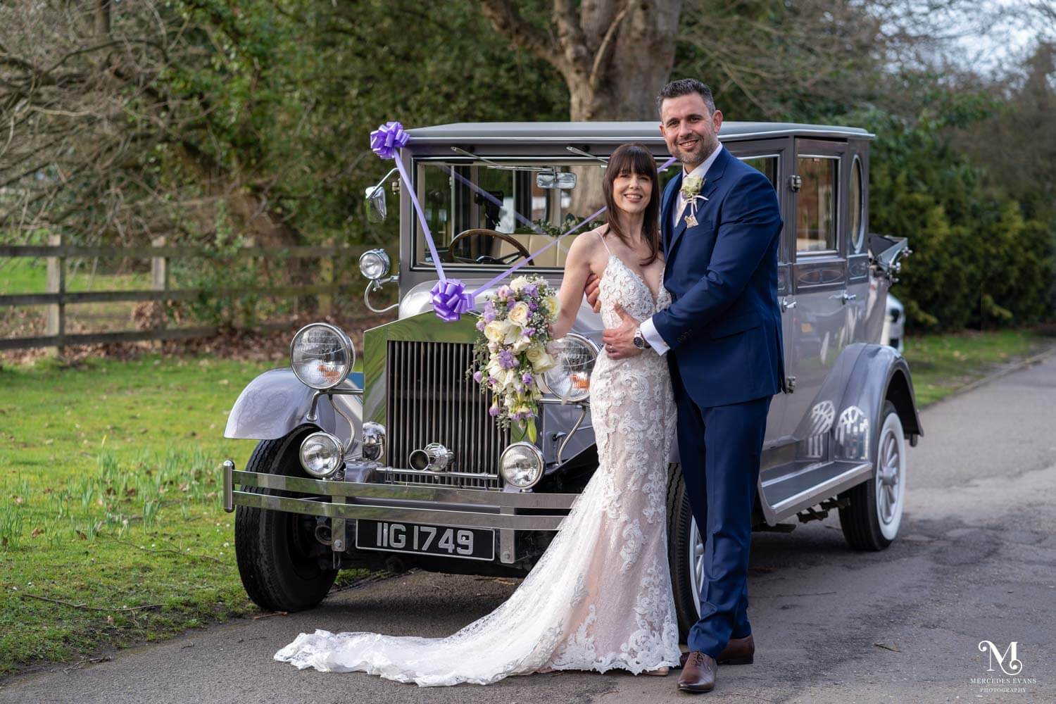 bride and groom pose next to the vintage wedding car