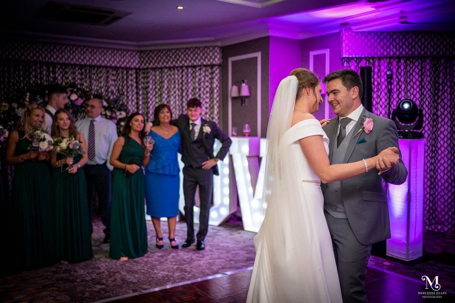 the bride and groom enjoy their first dance together as friends and family watch