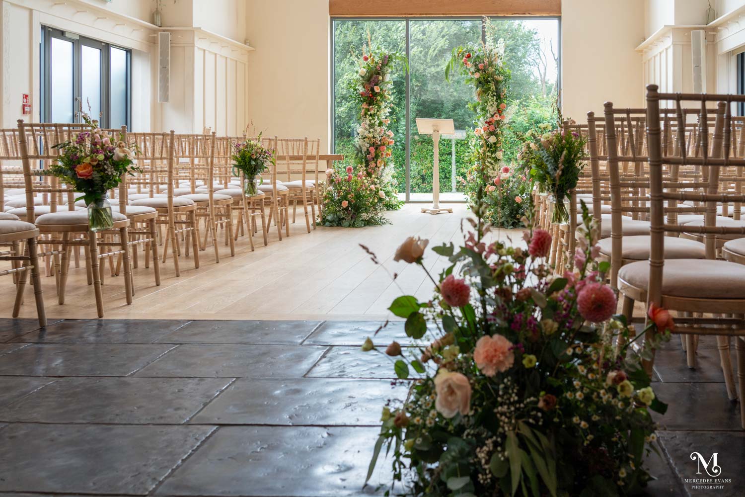 The ceremony room at Millbridge Court, set for a wedding with chiavari chairs and summer flowers