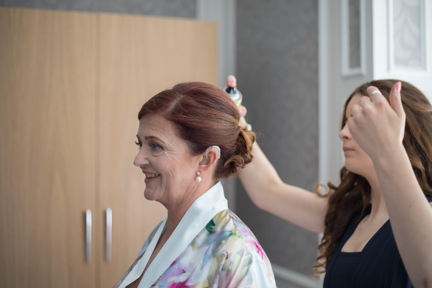 the hairdresser sprays the bride's updo