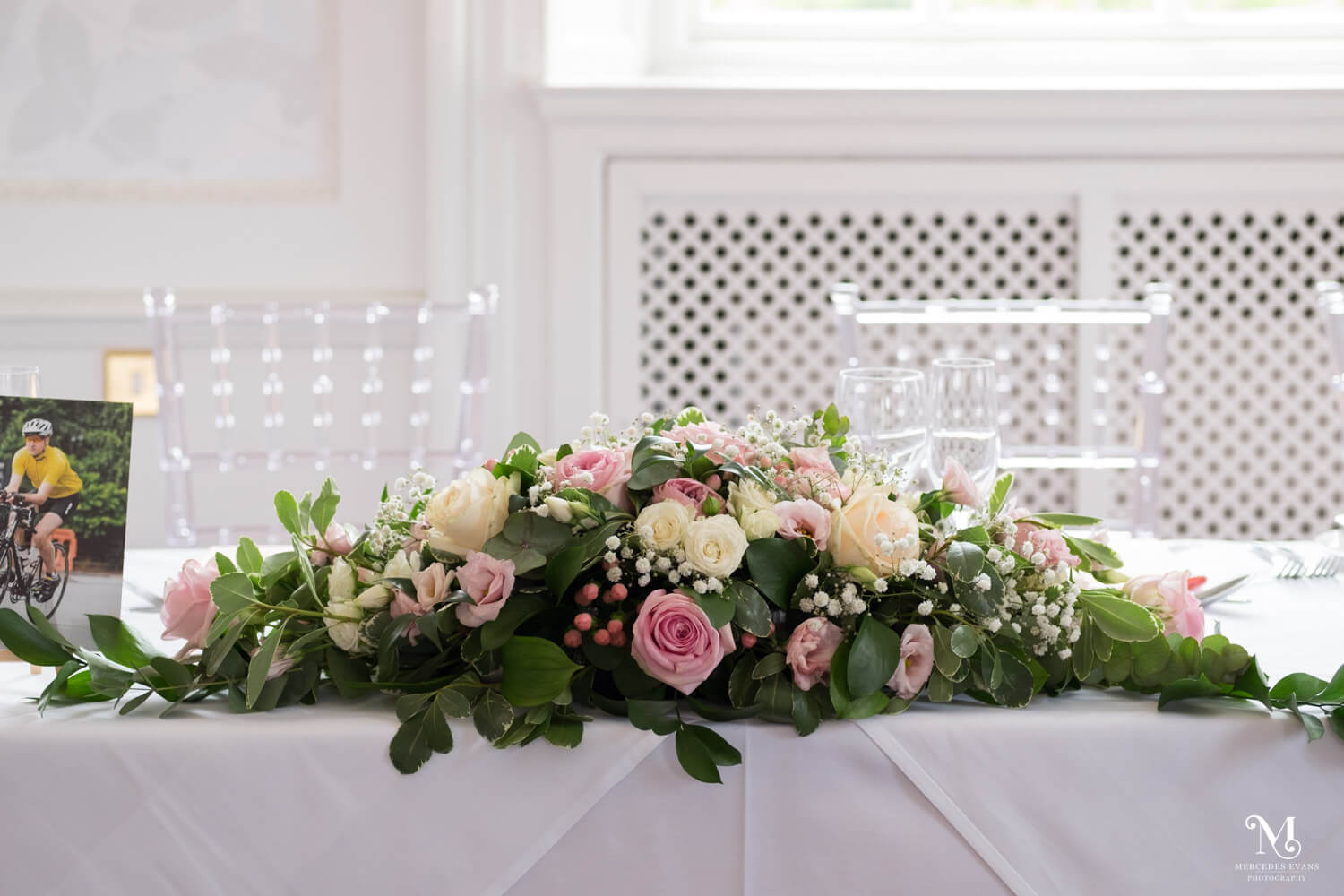 a long pink and white flower arrangement on a dining table