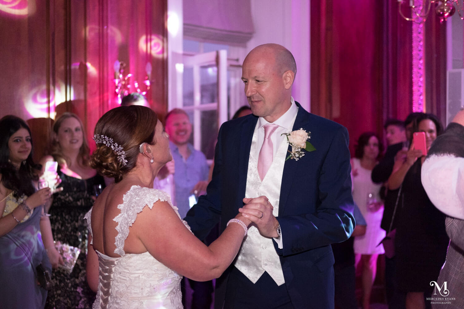 the bride and groom enjoy their first dance as their guests watch them