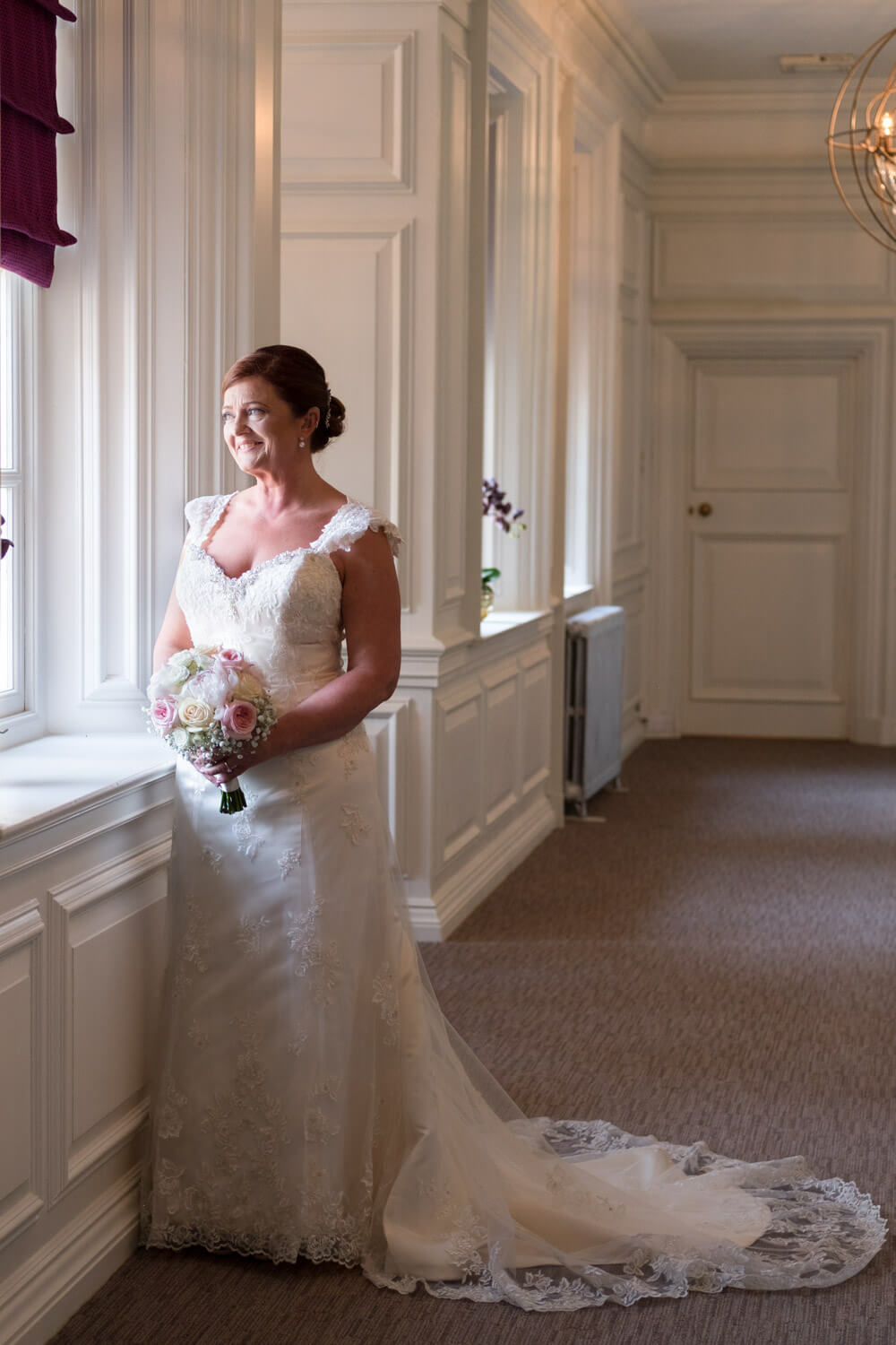 the bride stands looking out of the window in the upstairs hallway at Barnett Hill Hotel