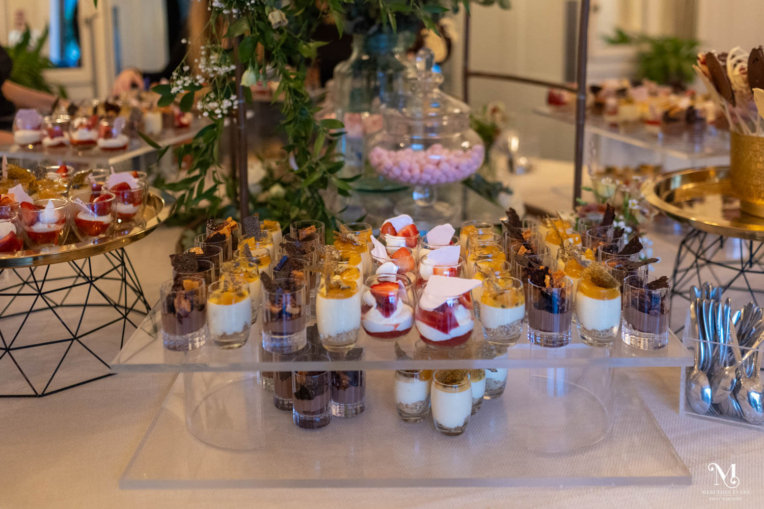 multiple rows of individual puddings in glasses are displayed, with bonbons and chocolate lollipops