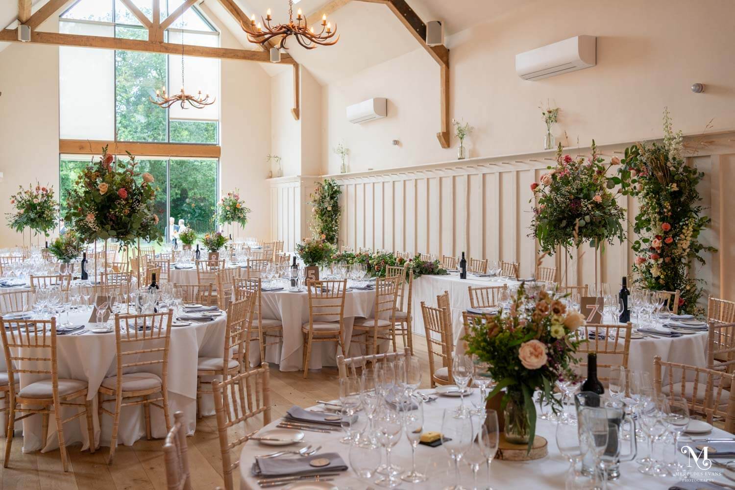 The larger of the two halls at millbridge court set ready for the wedding breakfast, there is a long trestle table by one wall and the room is filled round tables and chiavari chairs