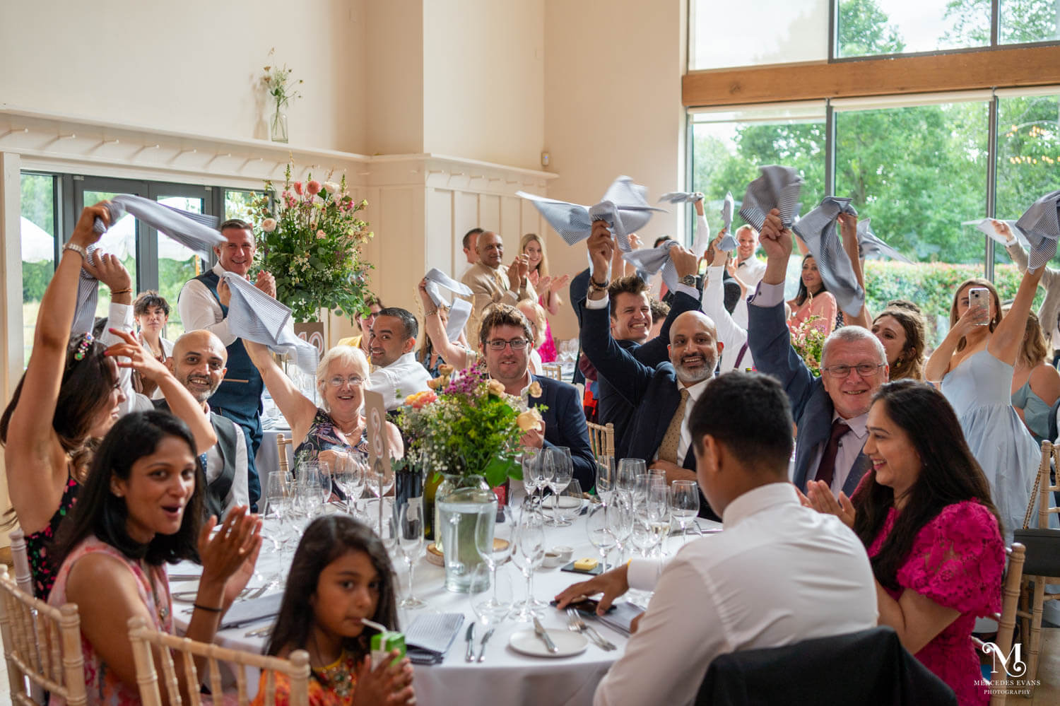 smiling wedding guests wave their napkins and applaud