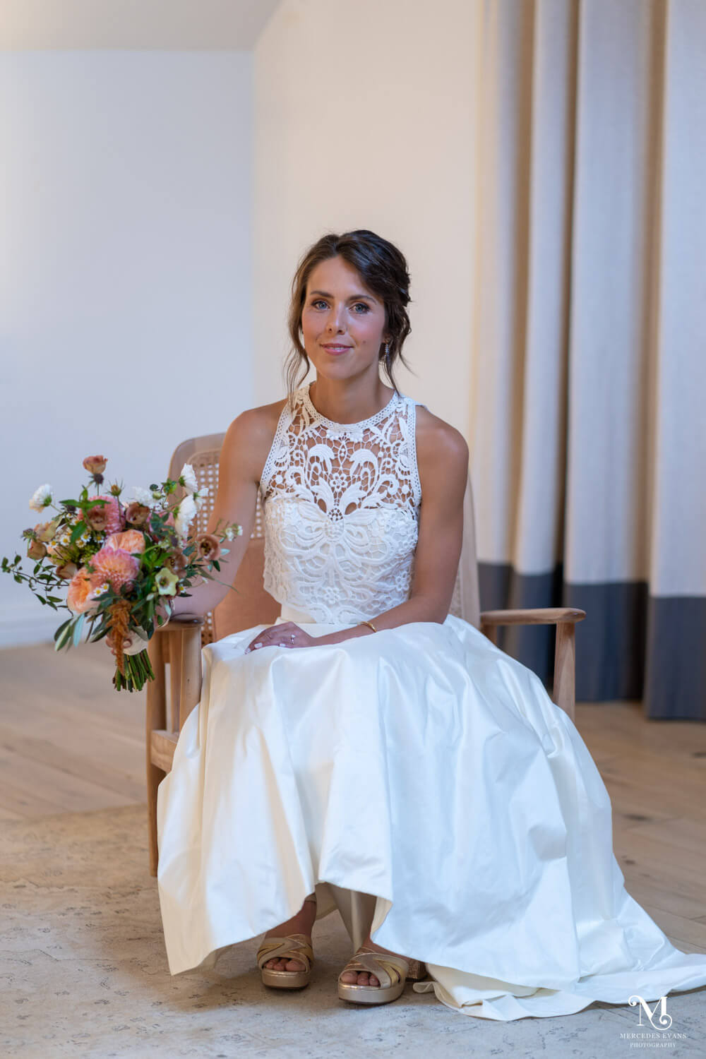bride sits in an armchair holding her wedding bouquet