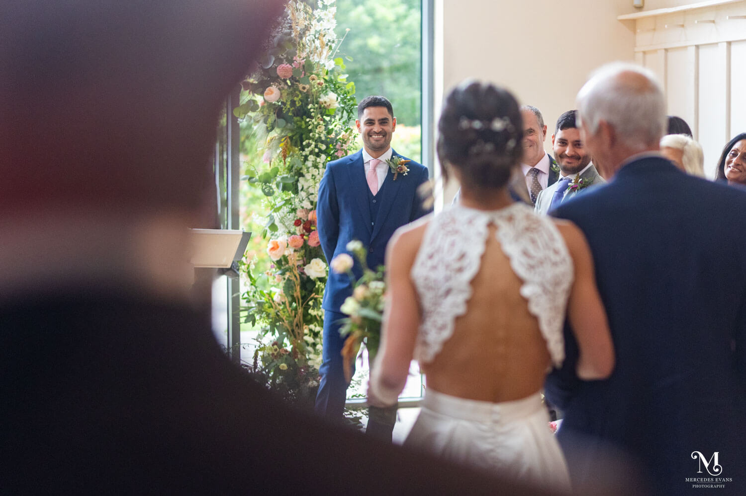 the groom watches his bride as she walks down the aisle in a modern wedding venue