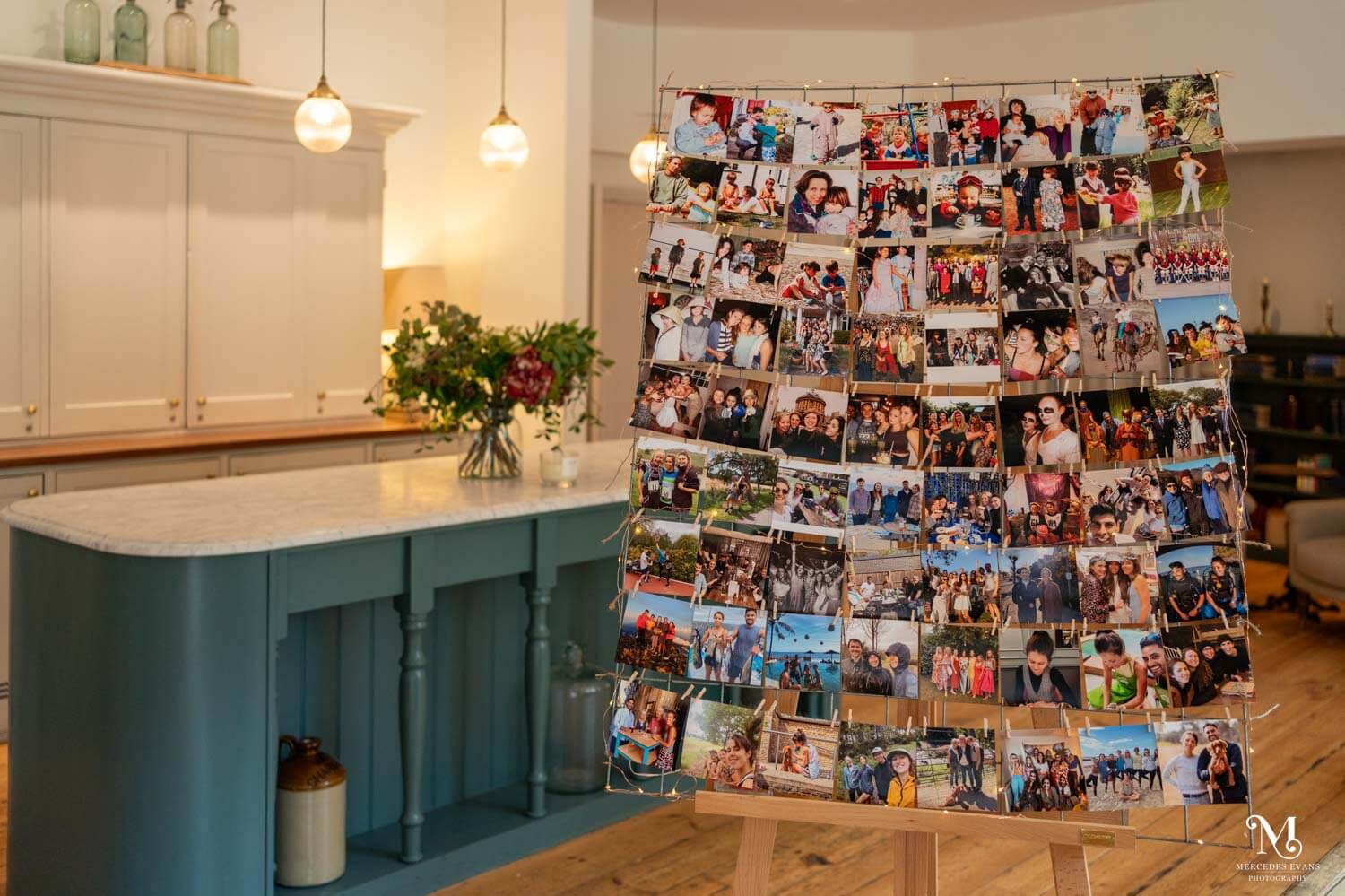 the lounge/kitchen area at millbridge court is decorated with lots of photographs that are pegged on a frame which stands on a large easel