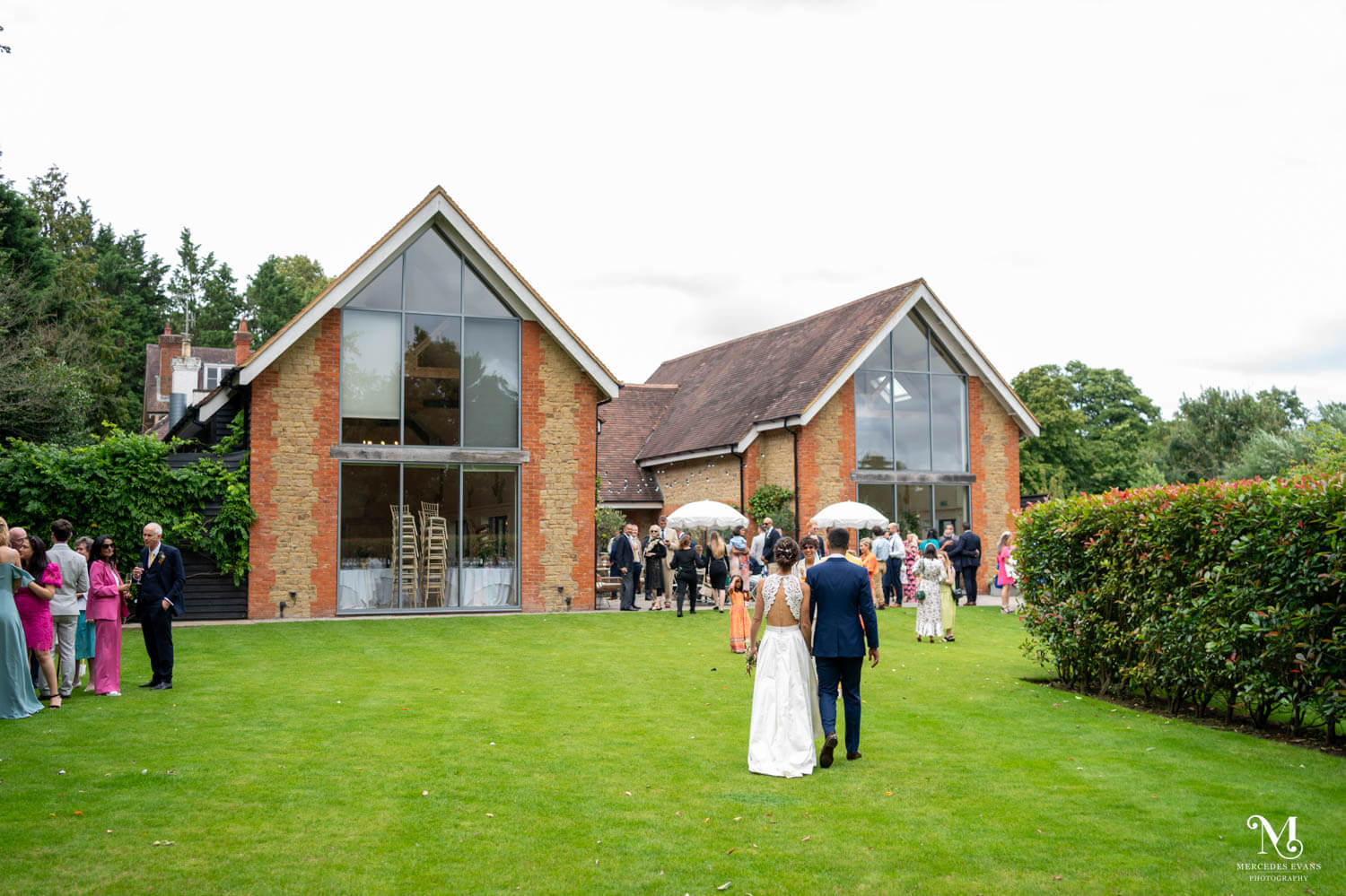 bride and groom walk hand in hand back towards their guests in the courtyard at millbridge court