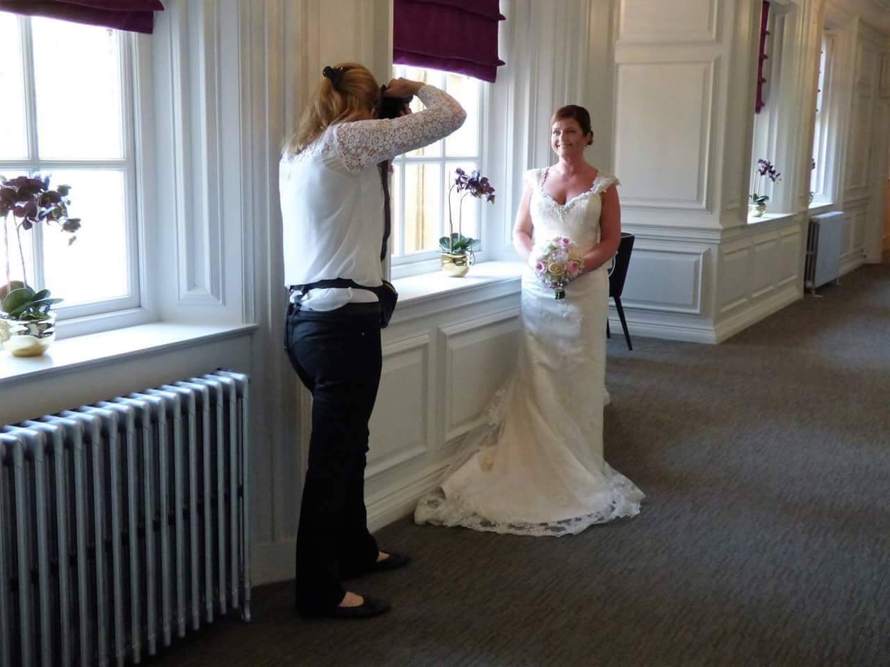 female photographer photographs a bride in a long corridor