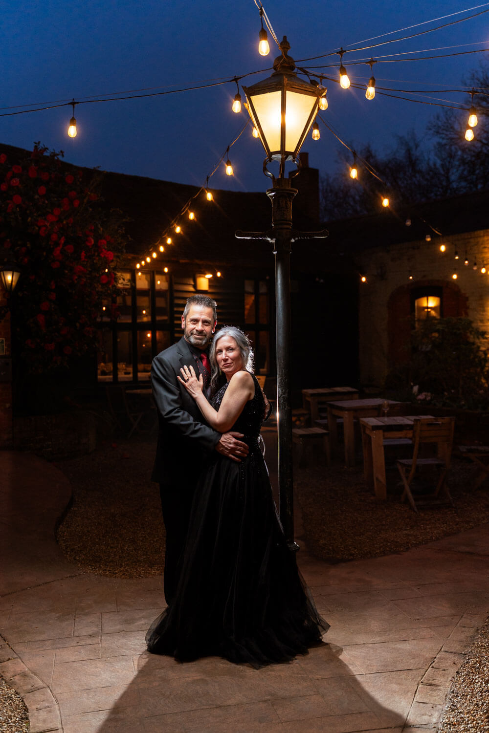 the bride and groom stand together under the lamp post in the courtyard outside the Briar Barn at Cantley house