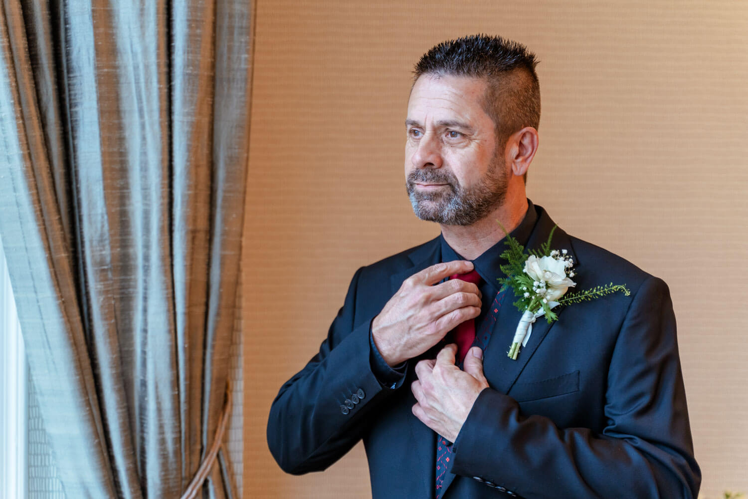 the groom tidies his red tie before the wedding ceremony