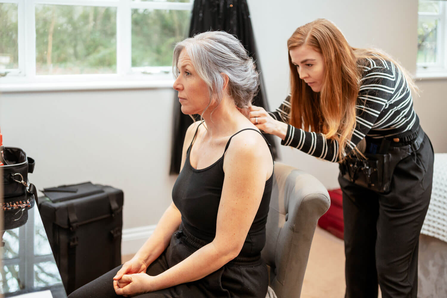 the hairdresser applies finishing touches to the bride’s hair as she sits by the window in room 38 at Cantley House
