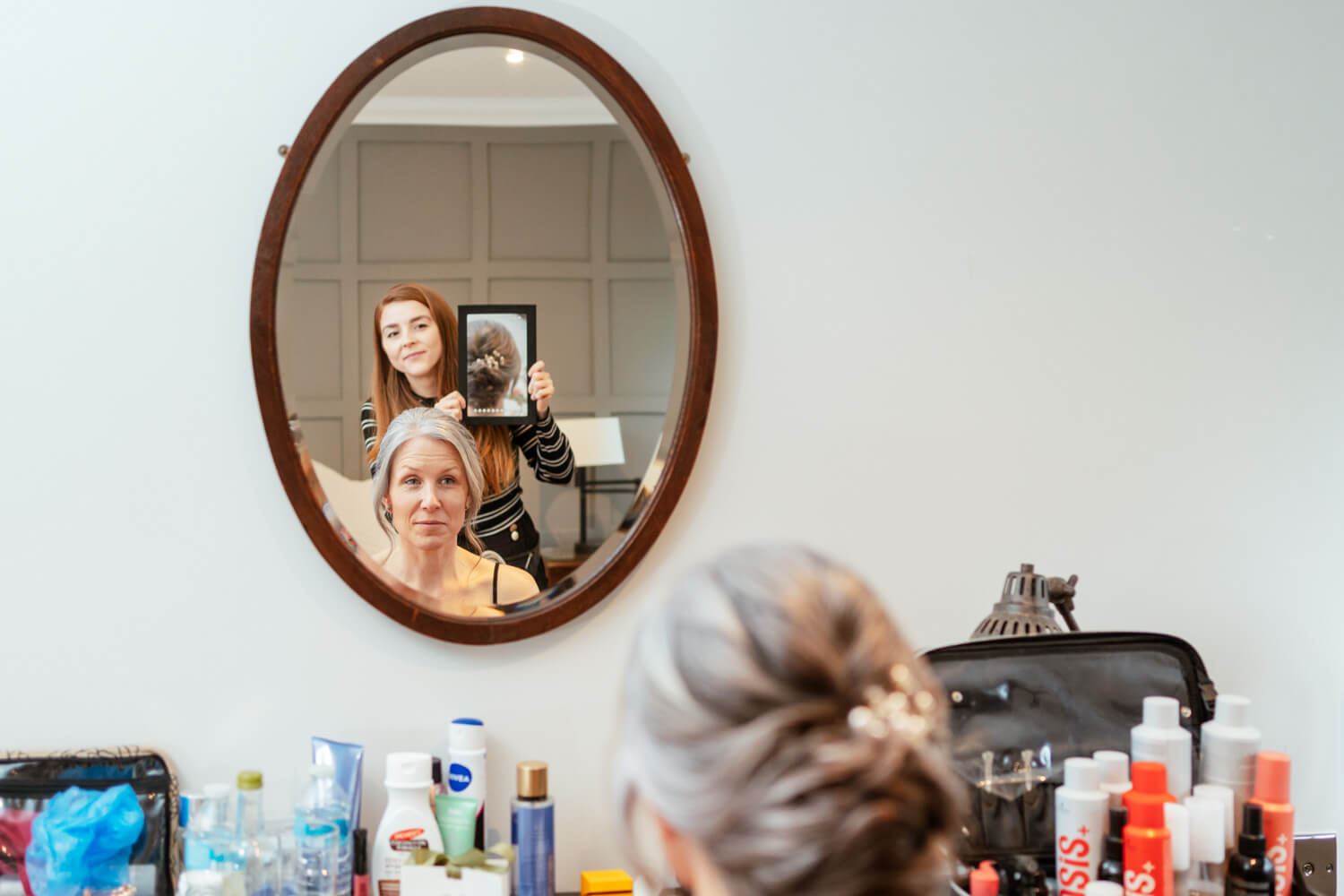 the hairdresser shows the bride the back of her hair in room 38 at cantley House
