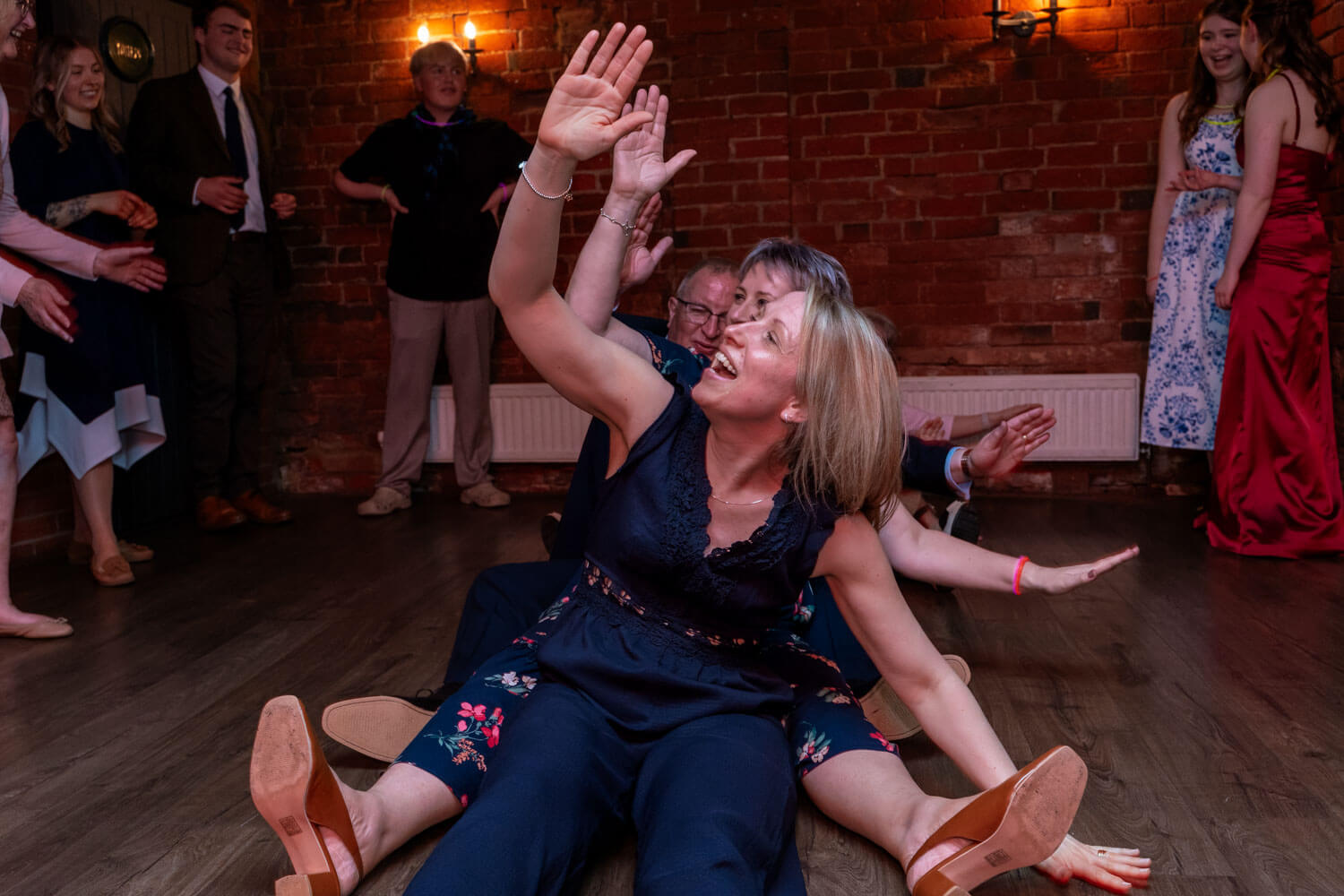 wedding guests sitting on the floor doing the Macarena dance